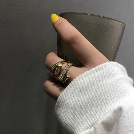 Hand holding a glass with yellow nail polish against a gray background