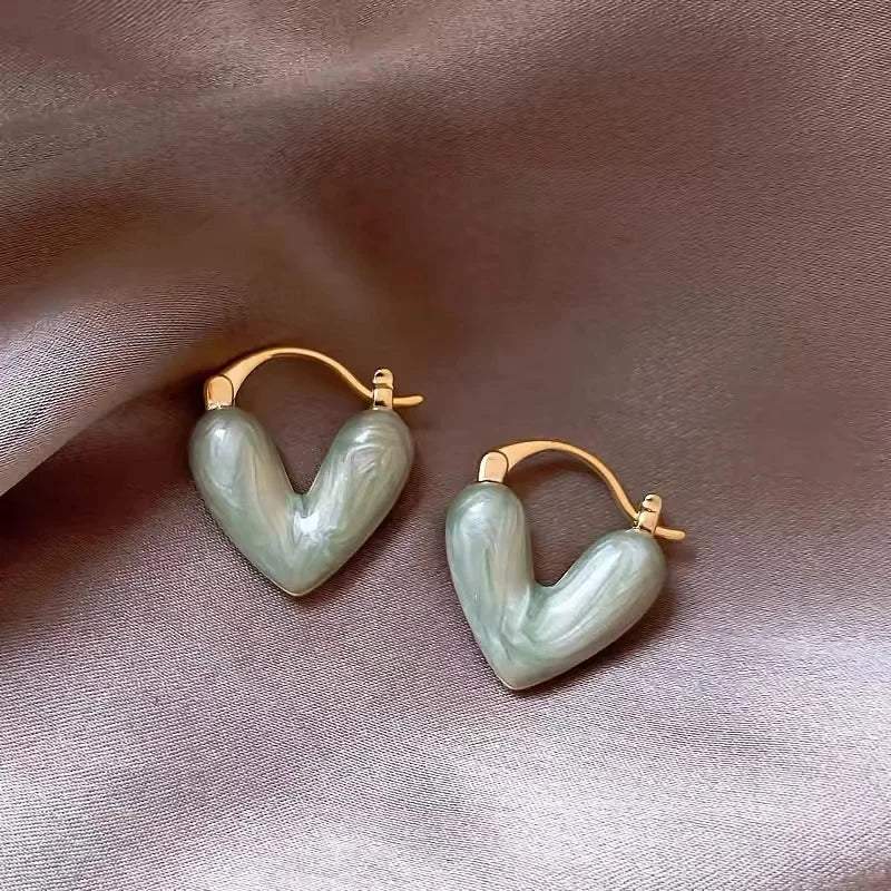 Heart-shaped earrings on a soft pink fabric background