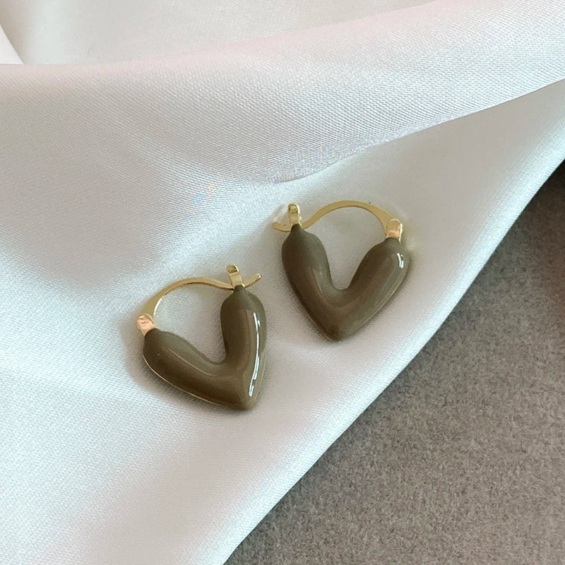 Heart-shaped earrings with gold rims on a white fabric background