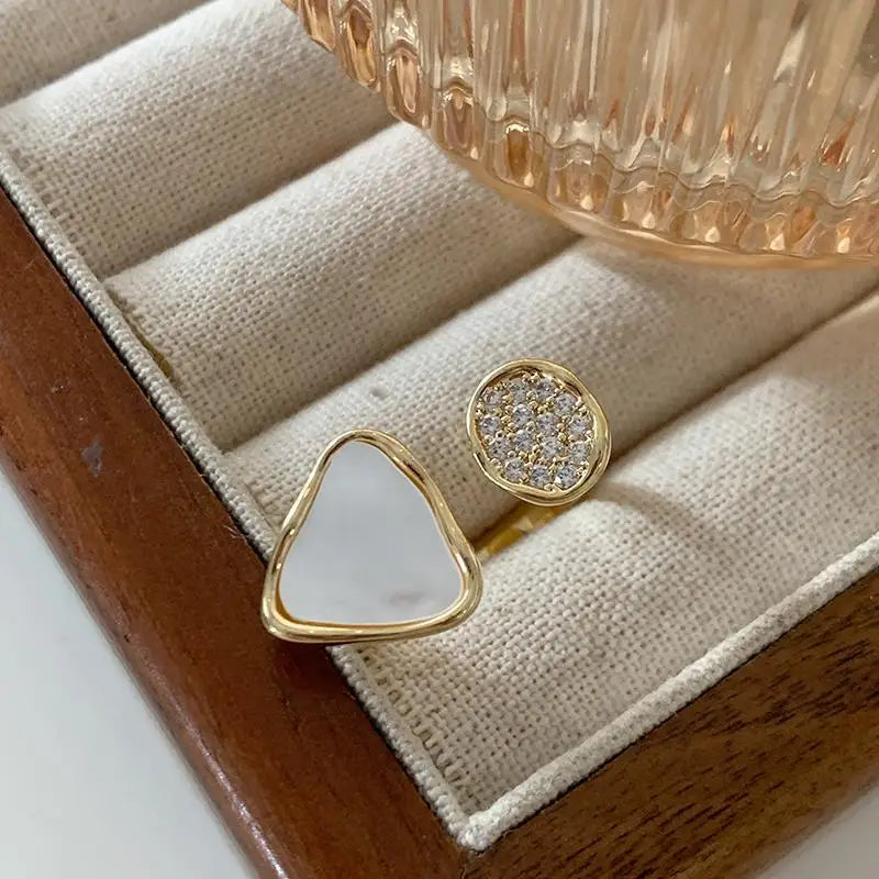 Two gold-rimmed rings with gemstones on a wooden jewelry box.