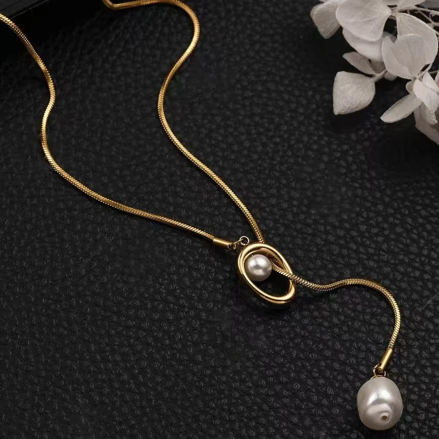 Gold necklace with pearls on a black textured surface