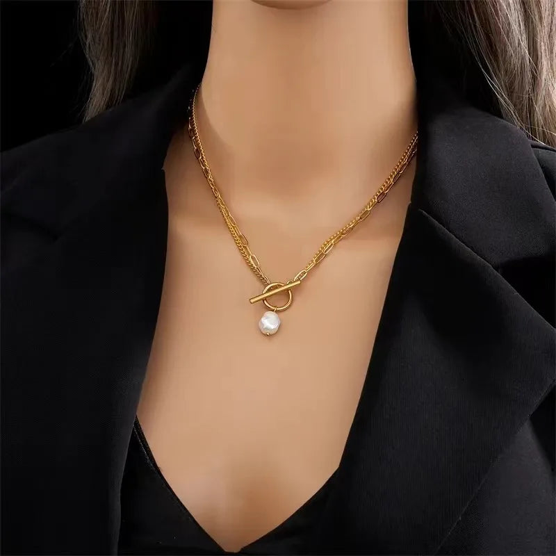 Gold necklace with a pearl pendant worn by a mannequin against a black background