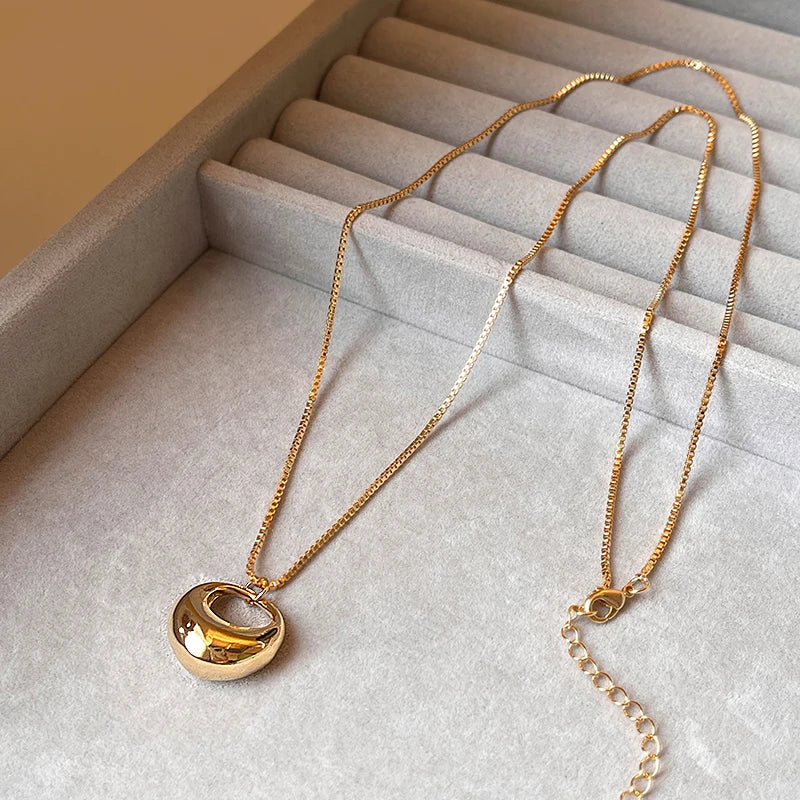 Gold necklace with a unique pendant on a textured surface