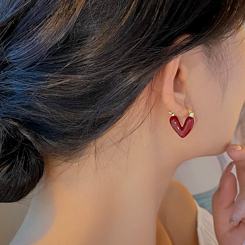 Heart-shaped earrings worn by a person with dark hair.