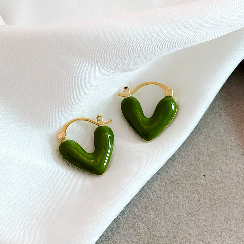 Green heart-shaped earrings on a white fabric background
