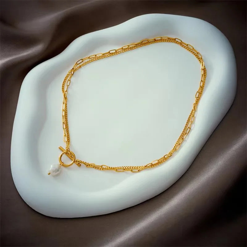 Gold chain necklace on a white stone surface with brown fabric background