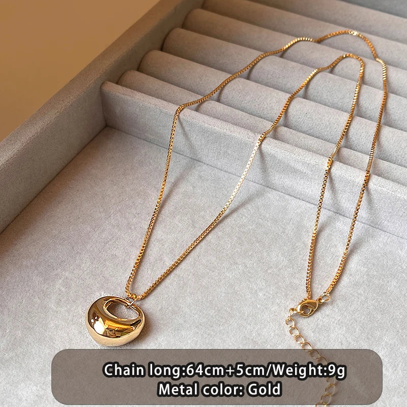 Gold necklace on a textured surface with product details.