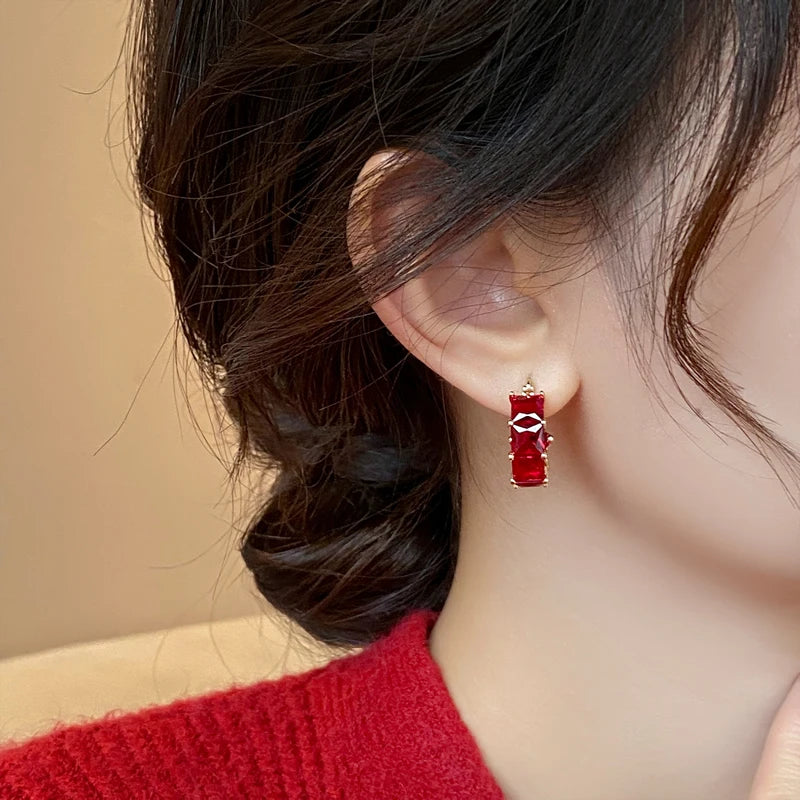 Close-up of an ear wearing a red earring with a blurred background