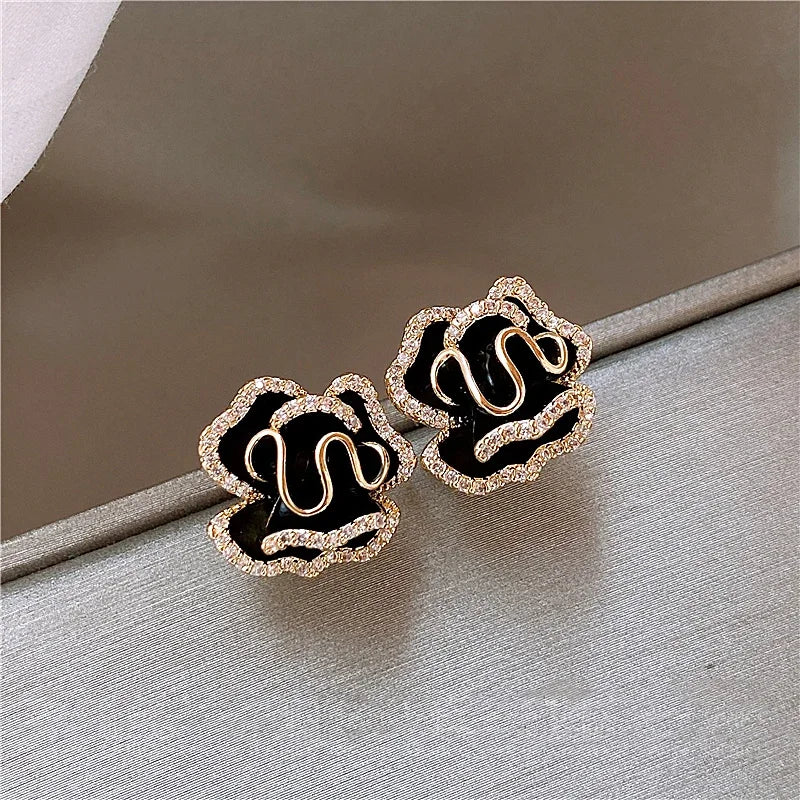 Pair of earrings with black centers and gold accents on a neutral background