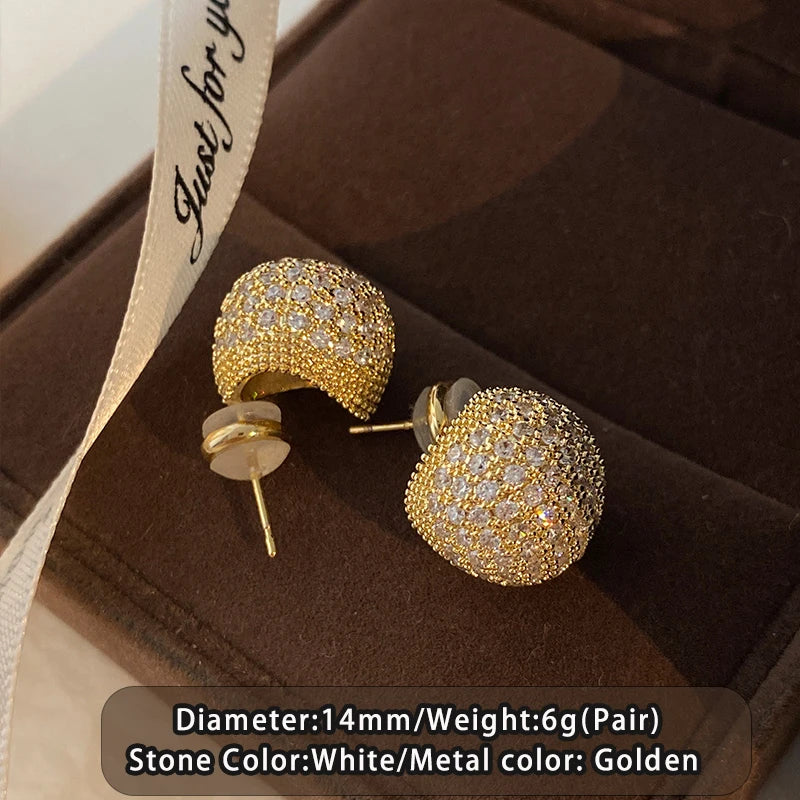 Gold earrings with white stones on a brown jewelry box