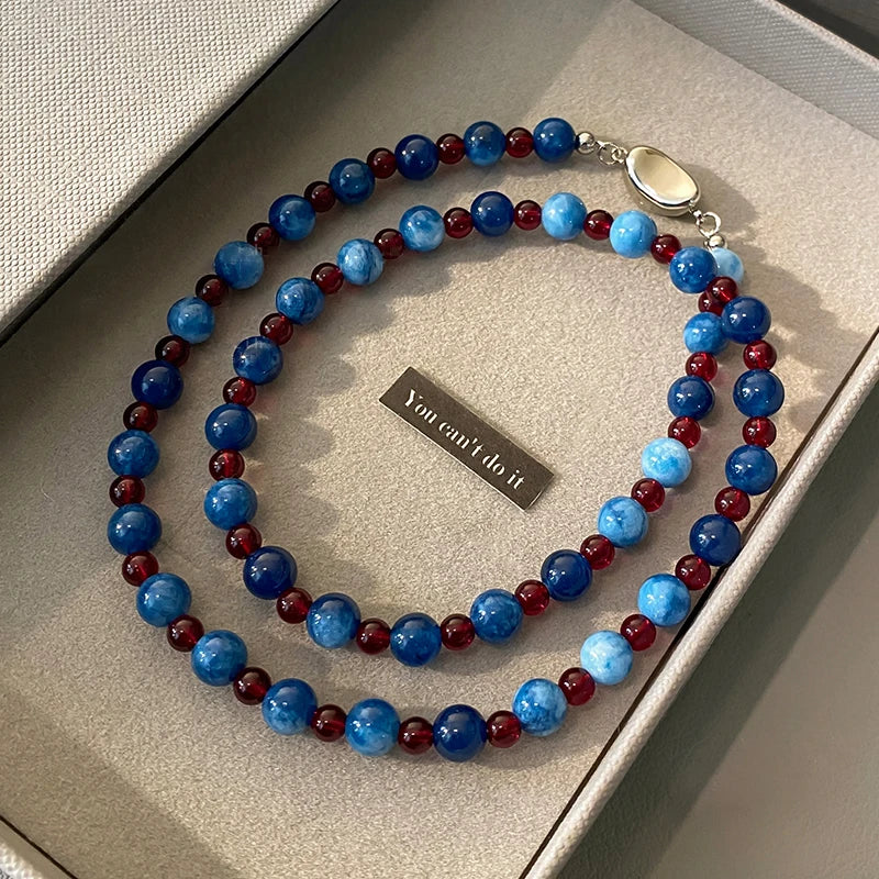 Beaded necklace with blue and red beads on a textured surface