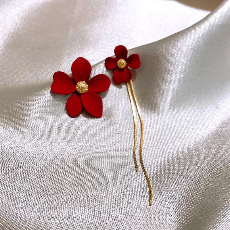 Red flower-shaped hairpin with gold center on a white satin background