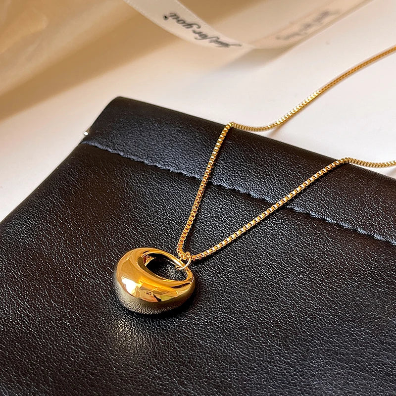Gold necklace with a round pendant on a black surface