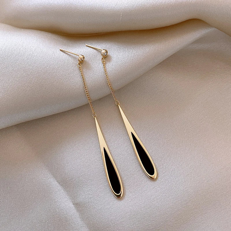 Gold earrings with black stones on a beige fabric background
