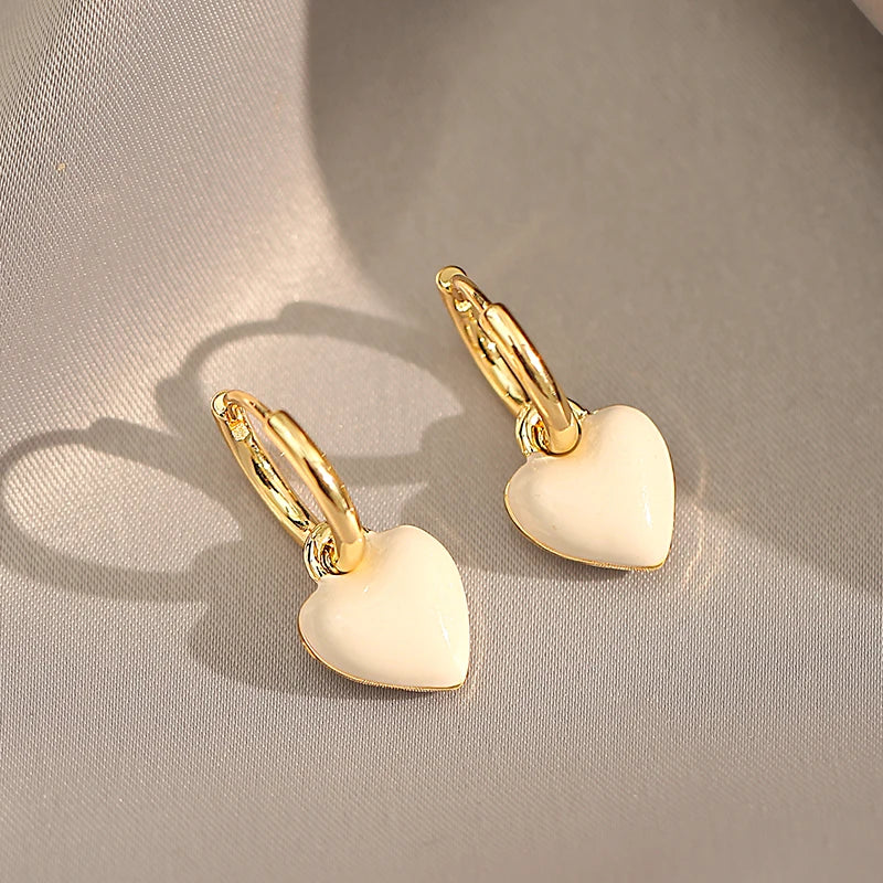Gold heart-shaped earrings on a beige fabric background