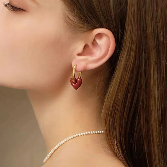 Heart-shaped earring worn by a person with a neutral background