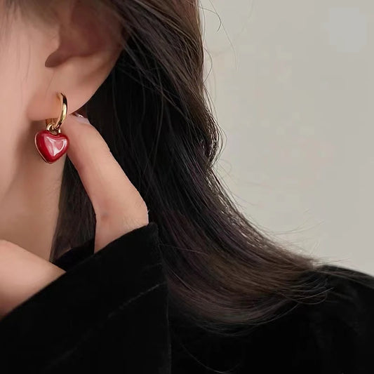 Red heart-shaped earring worn by a person with dark hair.