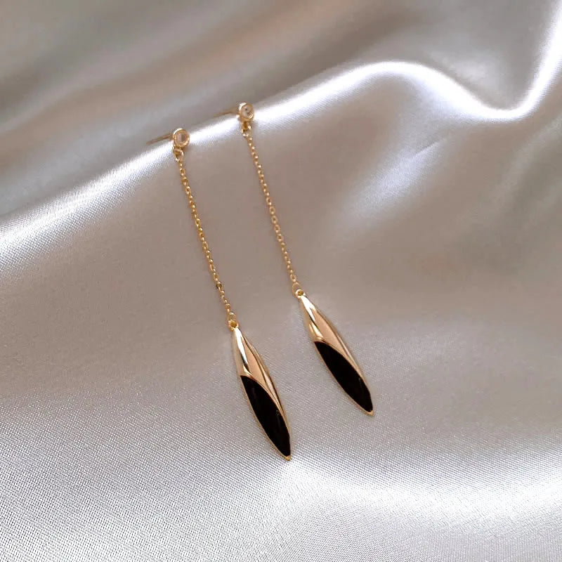 Gold and black earrings on a satin surface