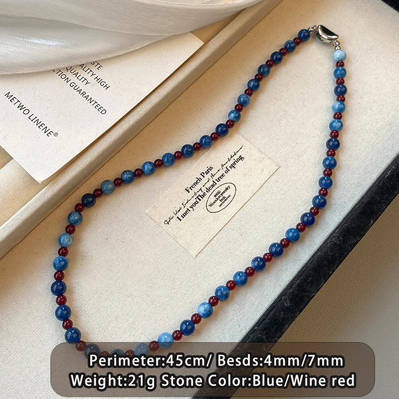 Necklace with blue and red beads on a white surface with a card.