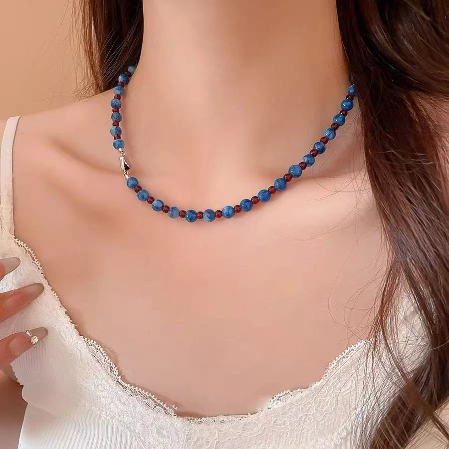 Necklace with blue and red beads on a model against a beige background