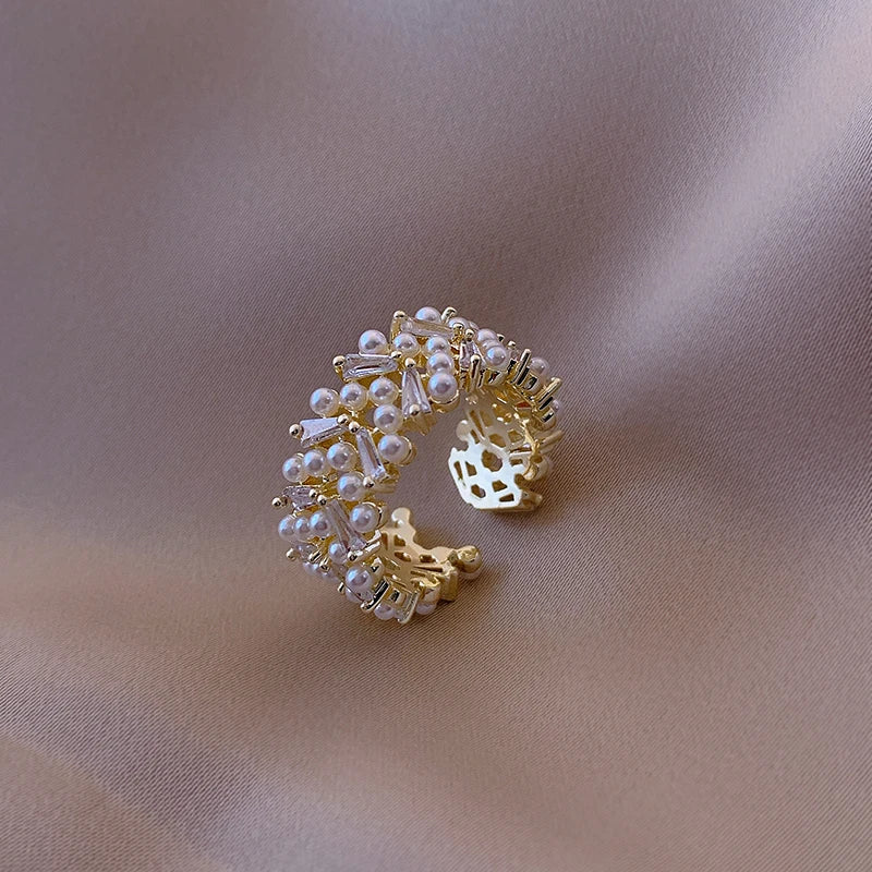 Gold and pearl ear cuff on a beige fabric background