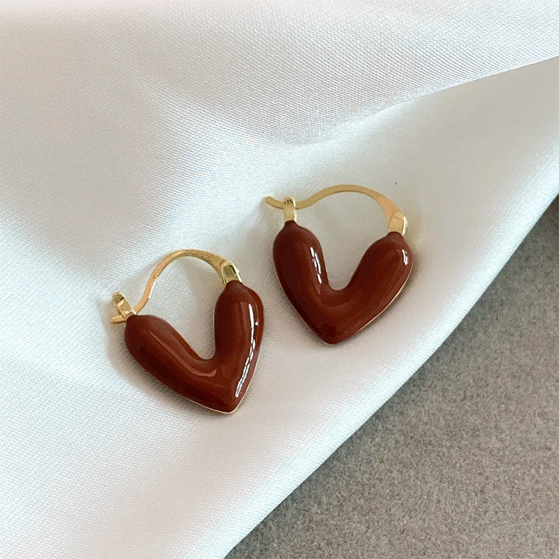 Brown heart-shaped earrings with gold accents on a white fabric background