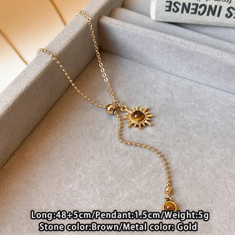 Gold necklace with a sun pendant on a light gray surface