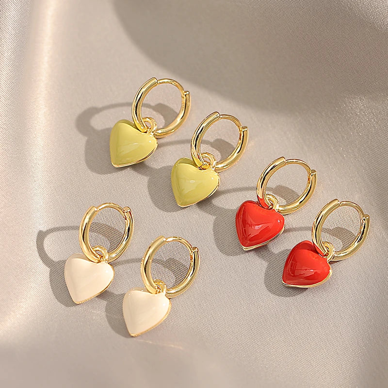 Set of heart-shaped earrings with gold hoops on a beige background