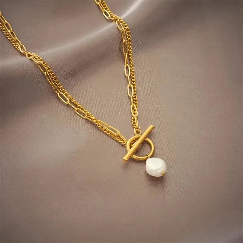 Gold necklace with a white pearl pendant on a brown fabric background