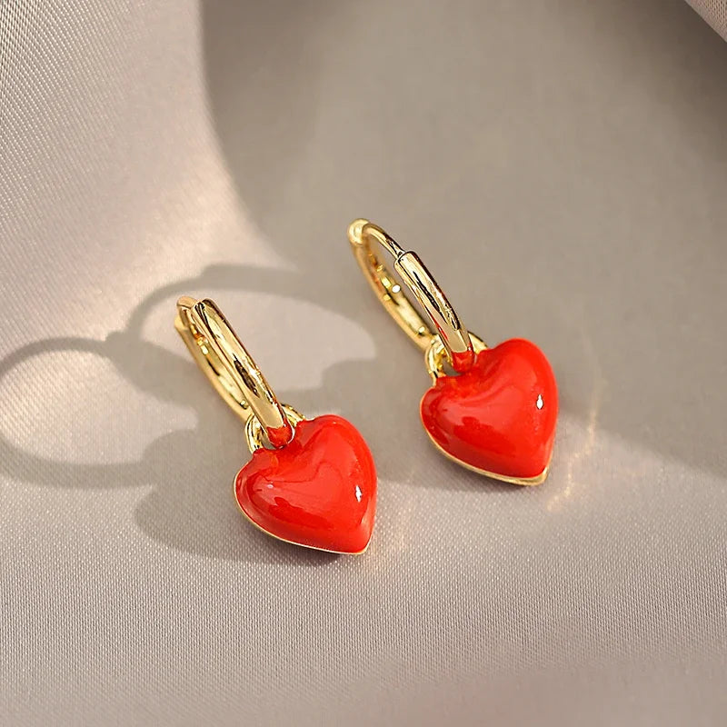 Red heart-shaped earrings with gold hooks on a light gray background