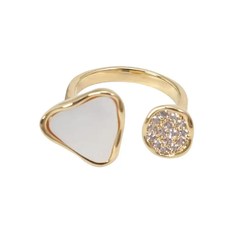 Gold ring with heart-shaped white stone and diamond-studded circular end on a white background